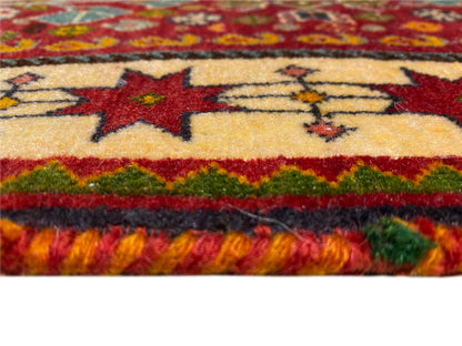 Borde de la alfombra en detalle: estrellas rojas sobre fondo beige, línea verde y flecos