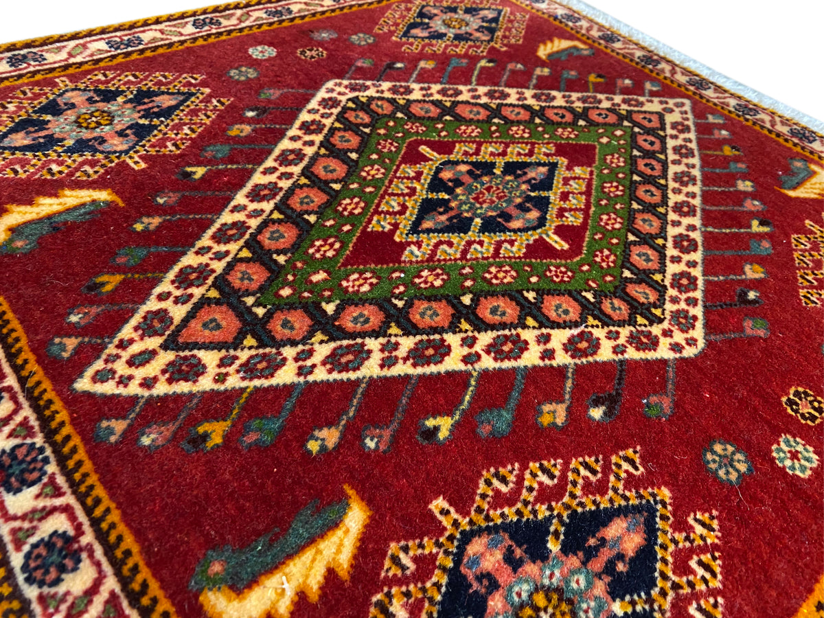 Detalle de alfombra Poshti: patrón rojo con medallón de colores y cenefa circundante
