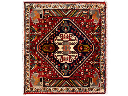 Alfombra oriental con fondo rojo, medallón azul oscuro y ornamentos geométricos