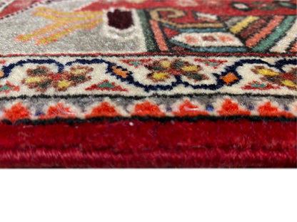 Primer plano: borde de alfombra con flecos, remate rojo y un denso diseño ornamental