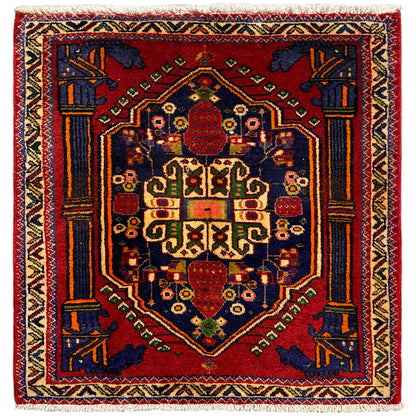 Alfombra Poshti, cuadrada, 66x62 cm, con diseño rojo y remates decorativos azules y amarillos.
