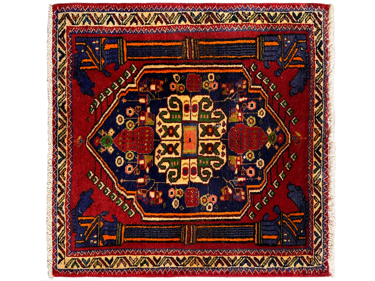 Alfombra Poshti de 66x62 cm con medallón central rojo y ornamento azul en las esquinas.