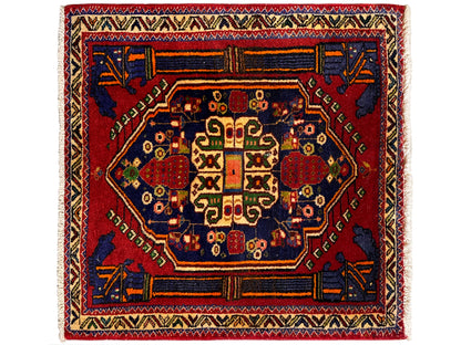 Alfombra Poshti de 66x62 cm con medallón central rojo y ornamento azul en las esquinas.