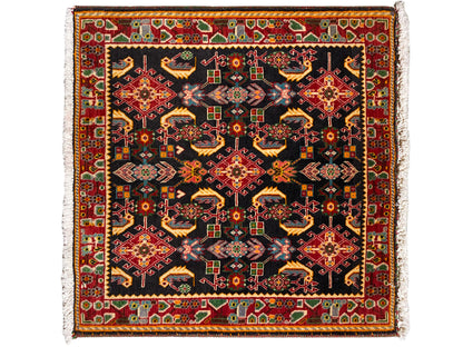 Alfombra con un patrón ornamental cuadrado, negro como base, con tonos rojos, amarillos y verdes