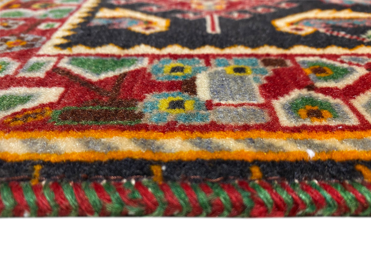 Alfombra con franja de borde de colores y flecos, rojo-amarillo-verde sobre una base negra