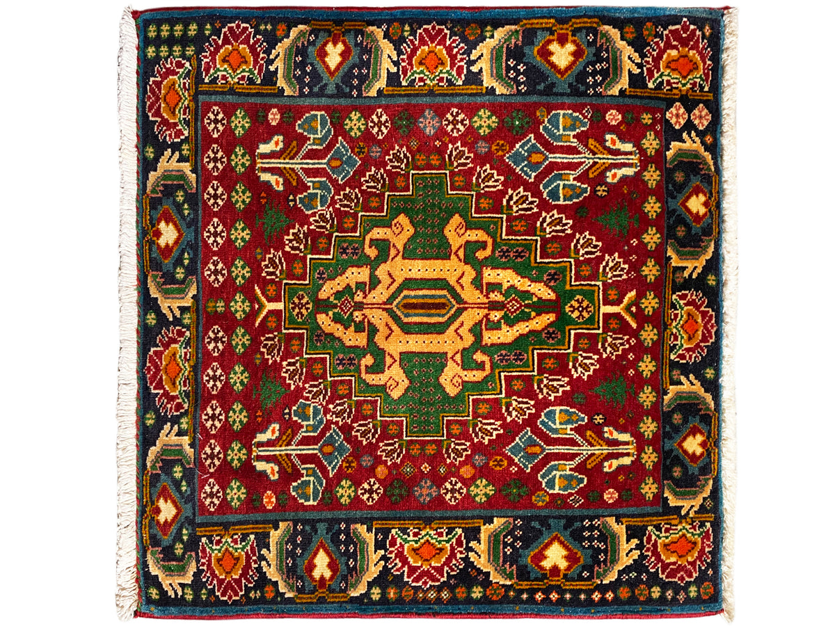 Alfombra rectangular (67x66 cm) con fondo rojo y cenefa de borde oscuro, con diseño geométrico