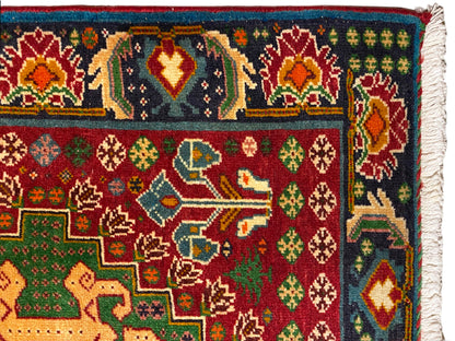 Primer plano de una alfombra: ornamentos coloridos sobre un fondo oscuro, motivos rojos y verdes, borde tejido