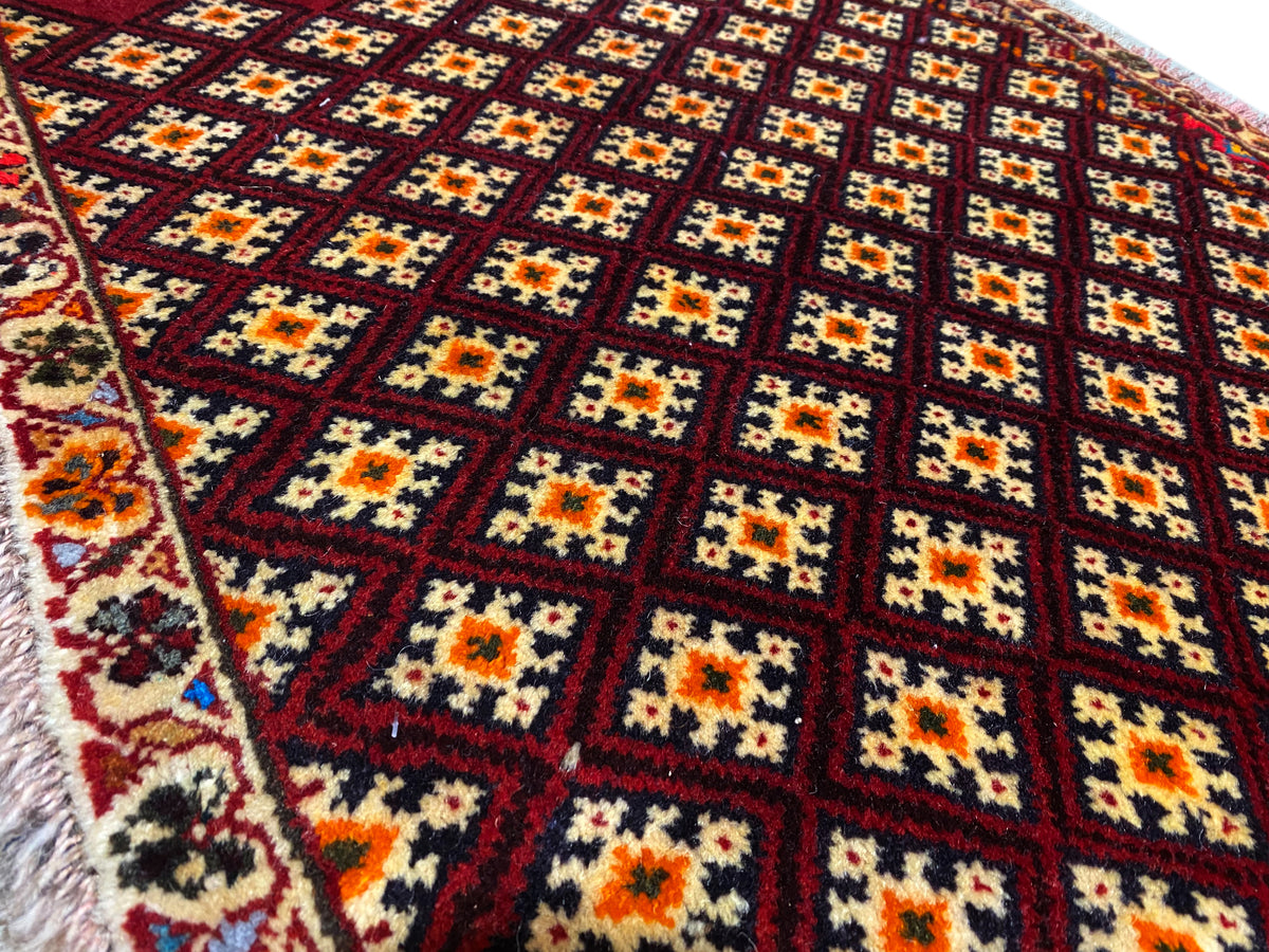 Alfombra Poshti de 61x59 cm: primer plano del estampado con rombos de colores sobre fondo rojo oscuro