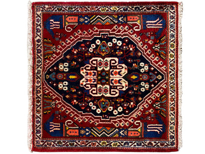 Alfombra rectangular con borde rojo, campo interior azul oscuro y patrón geométrico