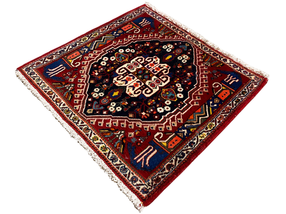 Alfombra con borde rojo y centro azul oscuro, adorno en forma de estrella, flecos