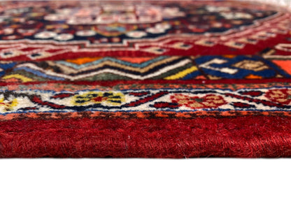 Detalle de una alfombra con un estampado colorido y un pelo alto de color rojo en el borde