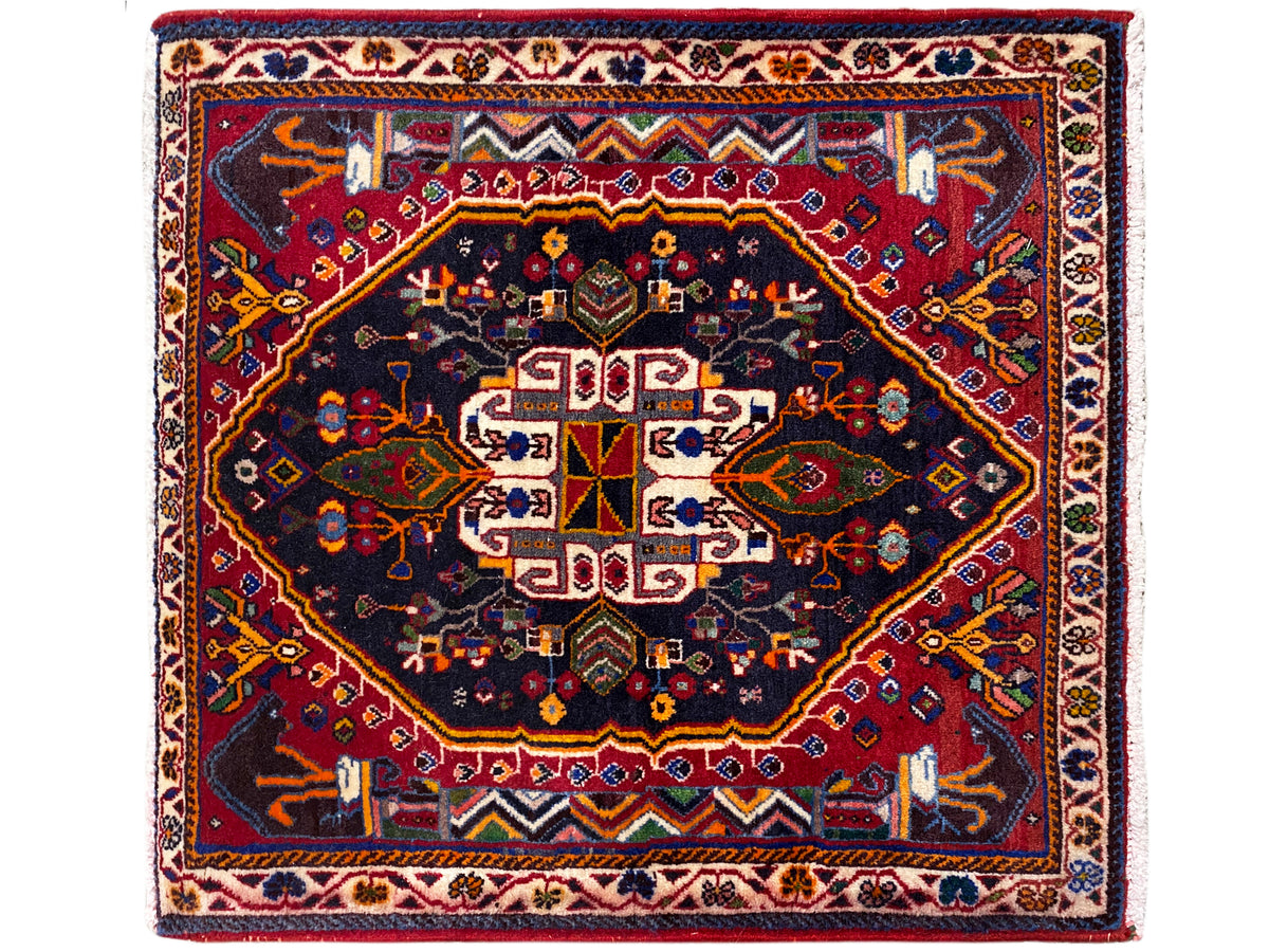 Alfombra cuadrada con fondo azul oscuro, marco rojo y ornamento centrado, 70x67 cm