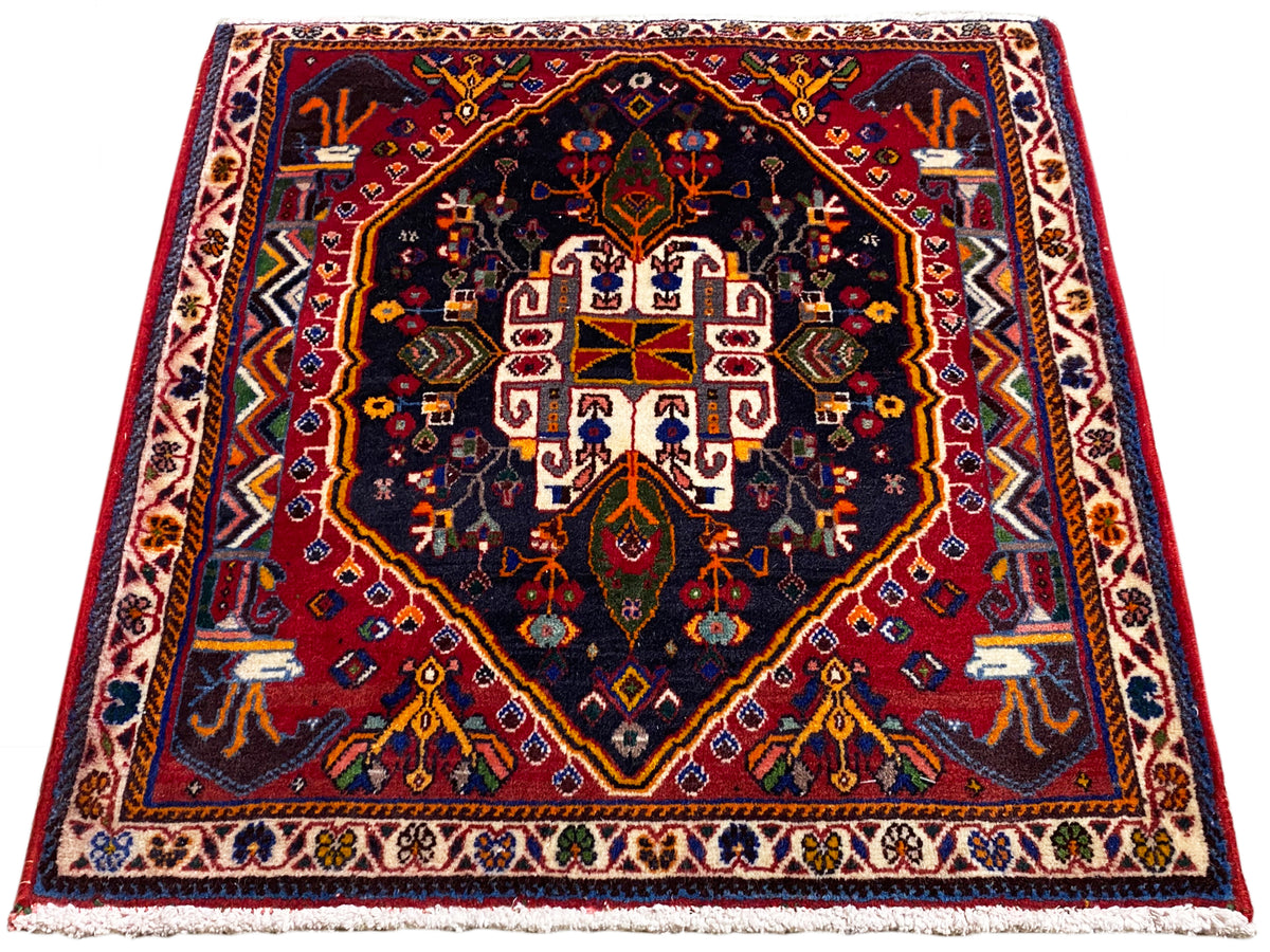 Alfombra de 70x67 cm con fondo azul oscuro, marco rojo y patrón de medallón simétrico
