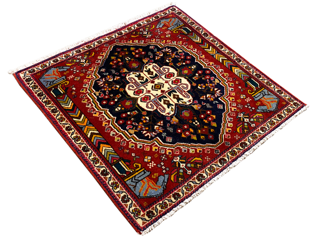 Alfombra Poshti de 65x61 cm, vista diagonal: fondo rojo con centro azul oscuro
