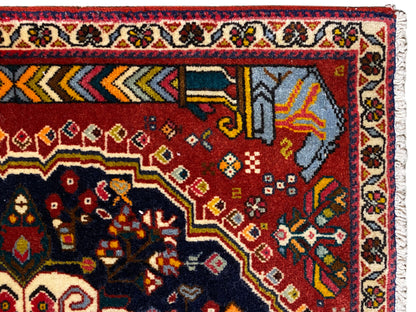 Alfombra Poshti 65x61 cm, detalle del borde: campo rojo con motivo turquesa grisáceo y remate blanco