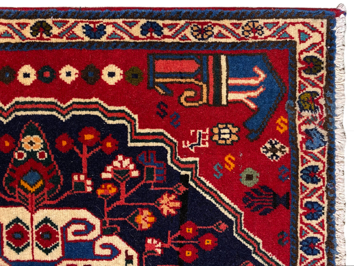 Esquina de alfombra con fondo rojo, símbolos de colores y marco decorativo azul