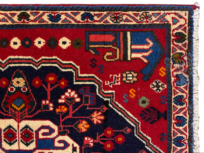 Esquina de alfombra con fondo rojo, símbolos de colores y marco decorativo azul