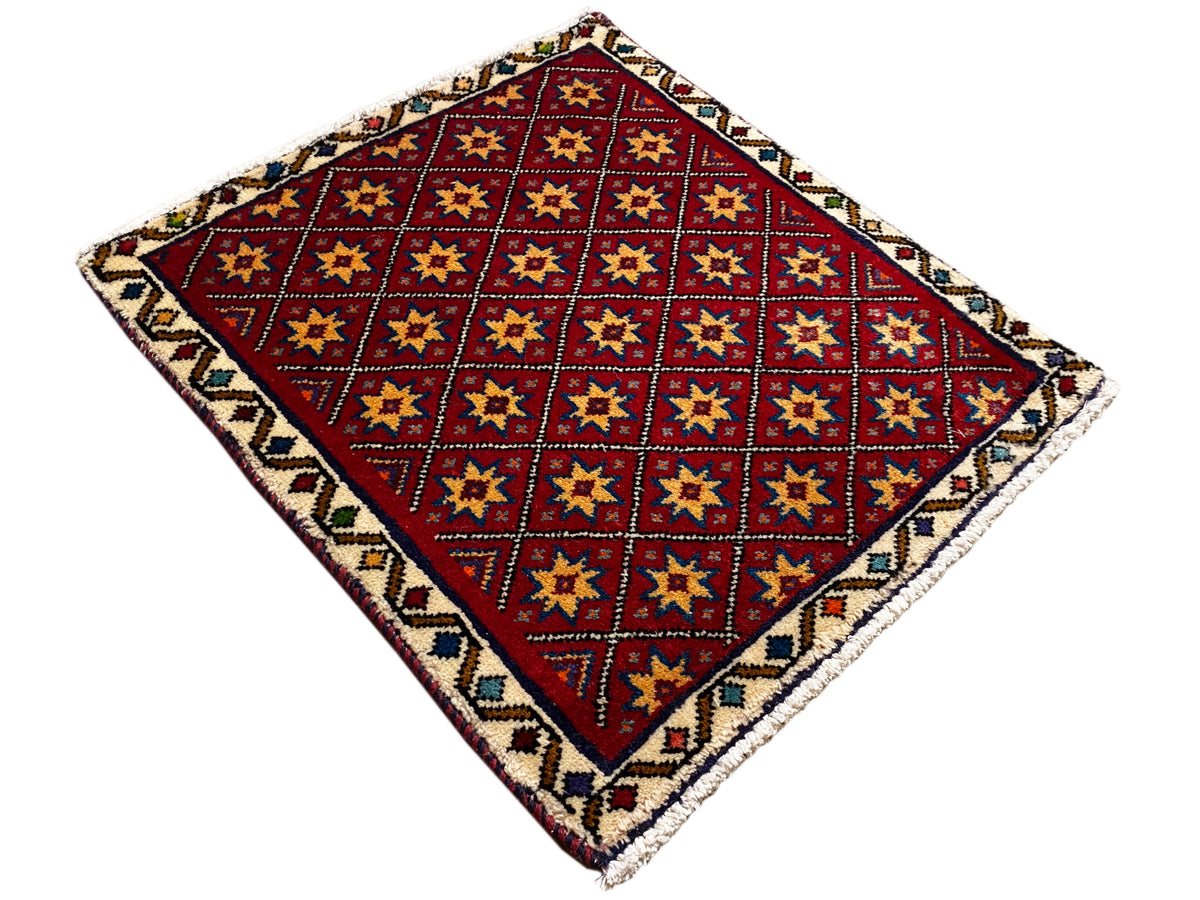 Alfombra cuadrada extendida con un patrón geométrico rojo y un borde colorido