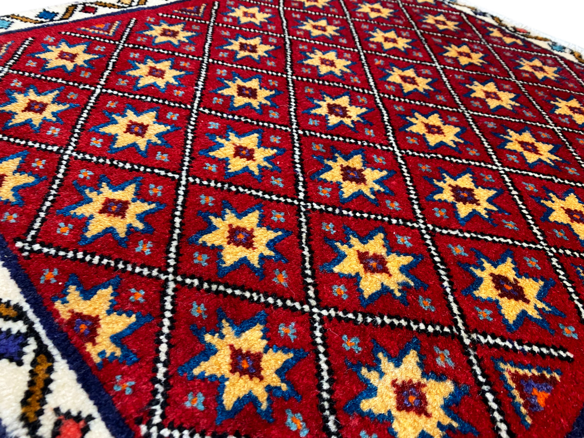 Primer plano de la alfombra: campo de rombos rojos con estrellas amarillas y azules