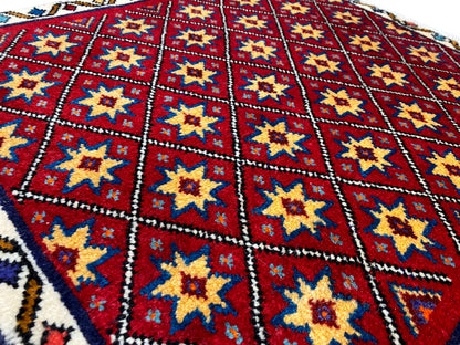 Primer plano de la alfombra: campo de rombos rojos con estrellas amarillas y azules