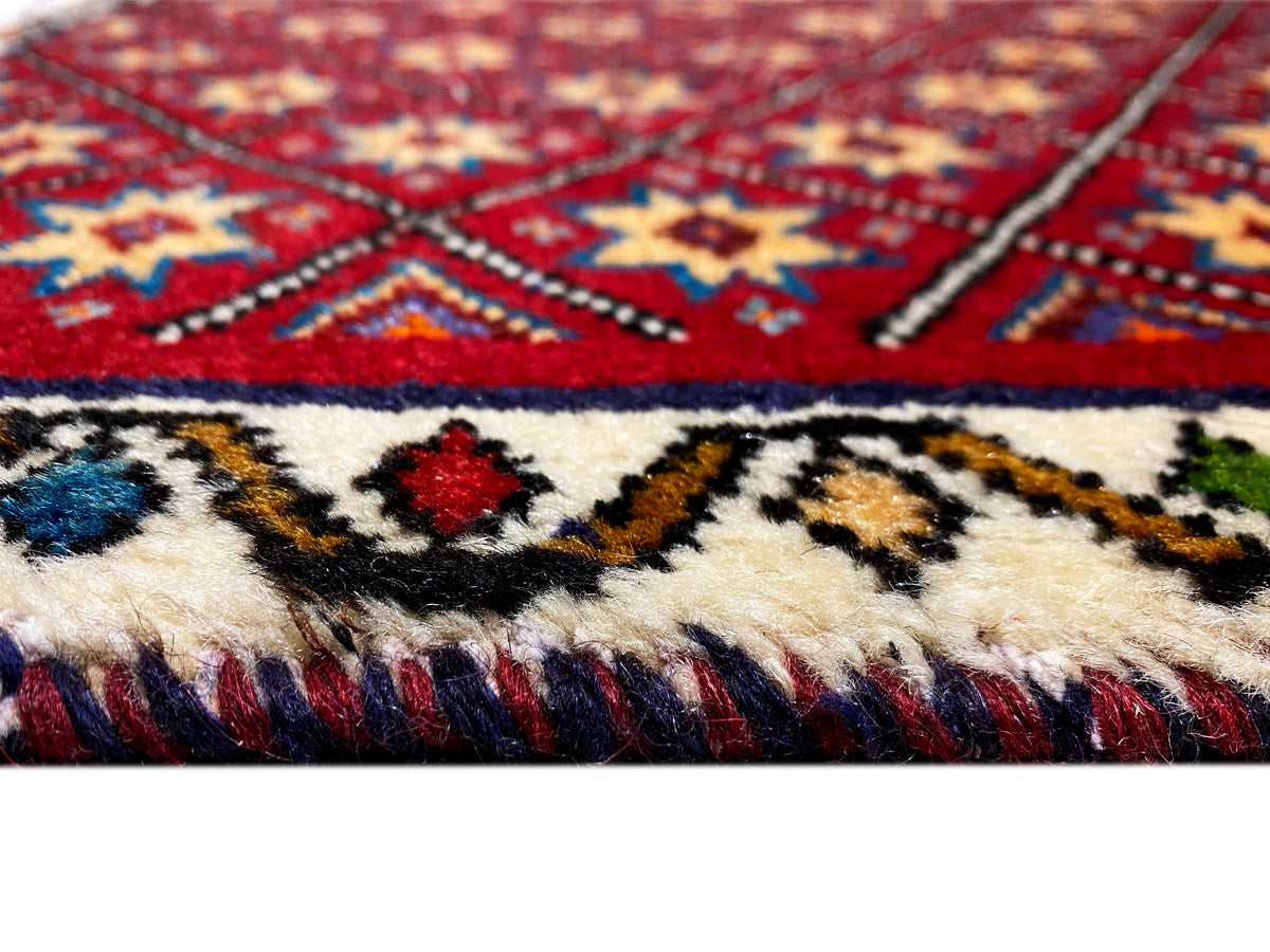 Detalle de la alfombra: patrón rojo y azul con flecos en el borde inferior